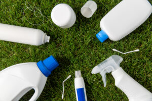 recycling, environment and ecology concept - close up of plastic and household chemicals waste on grass